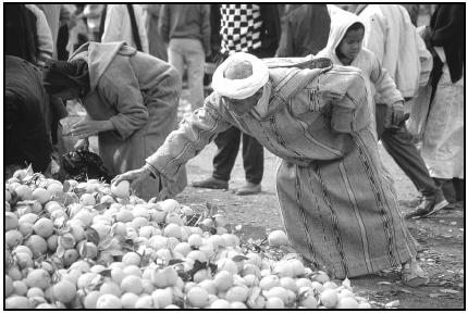 A shopper selects lemons from the stock at an open-air market. Moroccan cooking uses ingredients common to North Africa, such as lemons, olives, figs, dates, and almonds. Cory Langley