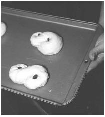 Form the dough for Lussekatter into S-shapes (like figure eights) and arrange the buns on a cookie sheet. Place a raisin in the center of each coil before baking. EPD Photos